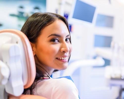 Female patient looking back in dental chair and smiling