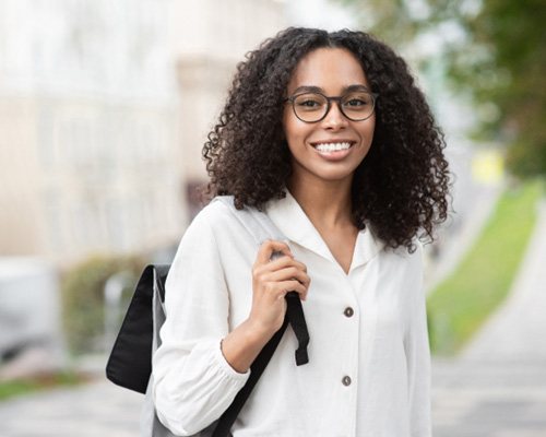 Woman in white shirt walking down street and smiling